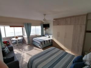 a bedroom with two beds and a living room at Seaview Self Catering Amanzimtoti in Amanzimtoti