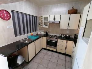 a small kitchen with white cabinets and a sink at Seaview Self Catering Amanzimtoti in Amanzimtoti +20 photos
