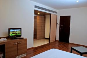 a bedroom with a television on a wooden dresser at Arpanaa Hotel in Tiruvannāmalai