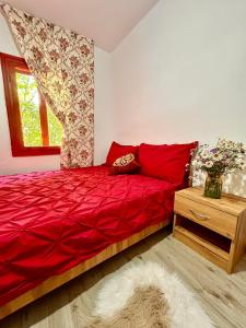 ein Schlafzimmer mit einem roten Bett und einem Fenster in der Unterkunft Căsuța Dede in Buzău