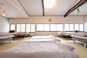 a large room with two beds and tables and windows at TOHANA Style ペット宿泊可能 カラオケルーム有り in Hanamaki