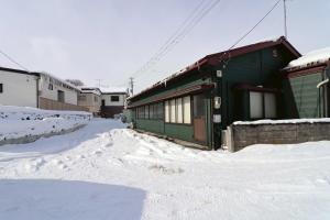 a green building with snow on the ground at TOHANA Style ペット宿泊可能 カラオケルーム有り in Hanamaki