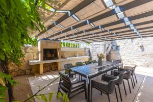 a patio with a table and chairs and a fireplace at Luxury Jerini House with pool and wellness in Bajčići