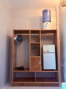 a wooden shelf with a refrigerator in a room at Jaydy Guest House in General Luna