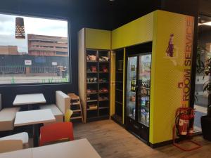 a restaurant with yellow walls and tables and a refrigerator at ibis budget London Hounslow in Hounslow