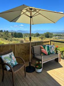 a patio with an umbrella and a chair and a bench at Flax Ridge in Hokitika Airport