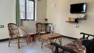 a living room with chairs and a table and a tv at Aralu in Bangalore