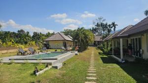 a house with a swimming pool in the yard at CharPoot Cottage Khao Lak in Khao Lak