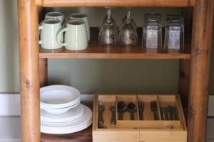 a wooden shelf with dishes and utensils on it at Little Amanzi in Pienaarsrivier +1 photo