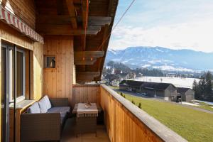 a balcony with a couch and a table and mountains at Ferienwohnung Vögel in Langenegg