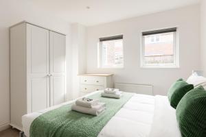 a white bedroom with a bed with towels on it at New! Bright 2BR Flat with Patio in Elmers End +10 photos