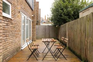 a patio with three chairs and a table and a fence at New! Bright 2BR Flat with Patio in Elmers End