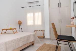 a white bedroom with a bed and a chair at Casa De Lago in Agios Nikolaos