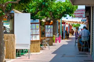 a street with shops and people sitting at tables at HOLIDAYLAND BAIE DES OLIVIERS VILLA 36m2 1chambre fermée 6 couchages ou VILLA 41M2 2chambres fermées 7 couchages in Narbonne-Plage +40 photos