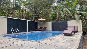 a swimming pool with two chairs and an umbrella at Pomma Holidays and Resorts in Muthanga
