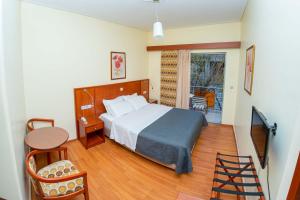 a bedroom with a bed and a table and a window at Hotel Ena - Elegant Mountain View Stay with Pool in Loutra Ipatis +17 photos