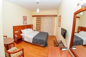 a hotel room with two beds and a television at Hotel Ena - Elegant Mountain View Stay with Pool in Loutra Ipatis