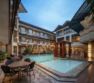 a pool with tables and chairs next to a building at Bentani Hotel & Residences Cirebon in Cirebon