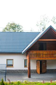une maison blanche avec une véranda et une terrasse dans l'établissement Domek Przy Strumyku, à Rajcza
