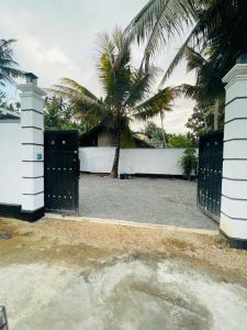 a driveway with two gates and a palm tree at Janaka Villa - Ahangama in Ahangama +4 photos