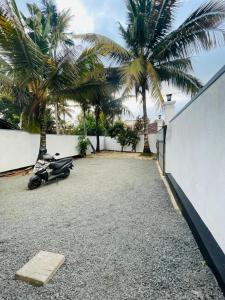 a scooter parked in a driveway with palm trees at Janaka Villa - Ahangama in Ahangama