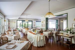 a restaurant with white tables and chairs and windows at Piccolo Hotel in Forte dei Marmi