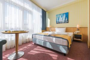 a hotel room with a large bed and a table at Strand-Hotel Hübner in Warnemünde