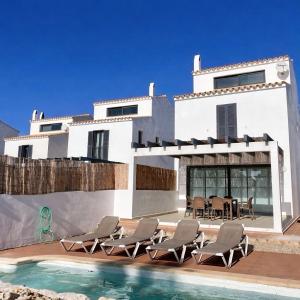 a white house with chairs and a swimming pool at Villa Son Blanc 5 in Sa Caleta