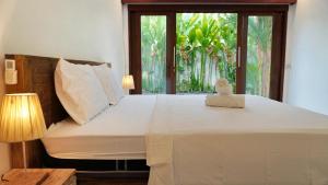 a bedroom with a large white bed with a window at Jepun Sesandan Cottage & Retreat by ABM in Selemadeg +51 photos
