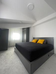 a bedroom with a large black bed with yellow pillows at King Size Apartment in Skopje