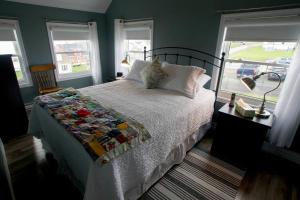 ein Schlafzimmer mit einem Bett mit weißer Bettdecke und zwei Fenstern in der Unterkunft Skipper Tom's in Twillingate