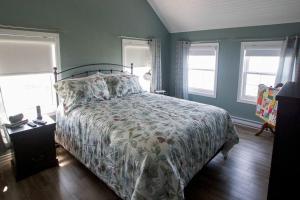 ein Schlafzimmer mit einem Bett mit Bettdecke und Fenstern in der Unterkunft Skipper Tom's in Twillingate