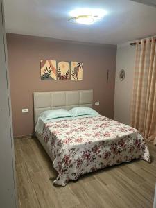 a bedroom with a bed with a floral bedspread at Meri Hause in Vlorë