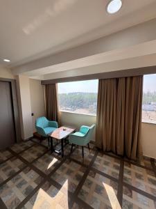 a room with a table and chairs and a large window at Hotel M Plaza New Digha in Digha