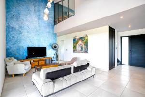 a living room with a couch and a tv at LA MAISON DES JADES in La Saline les Bains