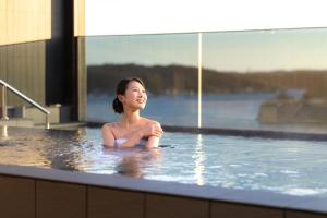 a woman is sitting in a bath tub at Ooedo Onsen Monogatari Premium Shima Saichoraku in Shima