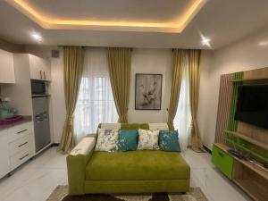 a living room with a green couch and a television at B-12 Apartments in Lagos +10 photos
