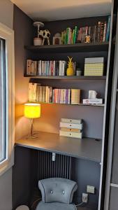 a book shelf with a chair and a lamp at Studio cosy à deux pas de Paris in Clichy