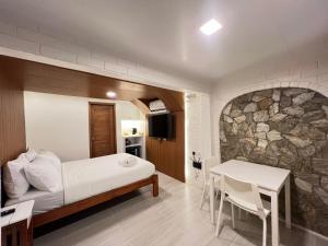 a bedroom with a bed and a stone wall at Casa Aya Suites in Puerto Galera