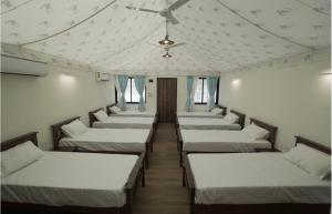 a row of beds in a room with a ceiling at Gaudham Periyar Farms in Jambhulpāda