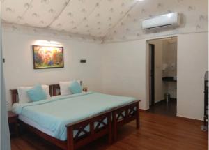 a bedroom with a large bed with blue sheets at Gaudham Periyar Farms in Jambhulpāda