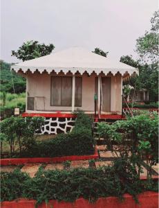a small house with a white roof in a garden at Gaudham Periyar Farms in Jambhulpāda