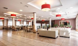 a restaurant with white tables and chairs and red lights at Hotel Austeria Conference & Spa in Ciechocinek