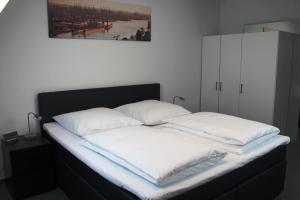 ein Bett mit weißer Bettwäsche und Kissen darauf in der Unterkunft Rooftop Apartment in Norderstedt