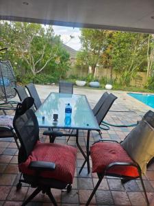 a glass table with chairs and a water bottle on it at 20 in Crescent in Gqeberha