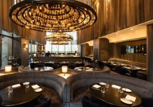 a restaurant with a large chandelier and tables and chairs at Sunlight Dormitory in Mumbai
