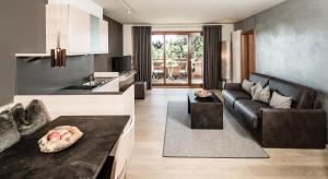 a kitchen and living room with a black couch at Josef Mountain Resort in Avelengo