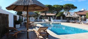 - une piscine avec des chaises longues et des parasols à côté de la piscine dans l'établissement Mas des Rièges & Spa, à Saintes-Maries-de-la-Mer