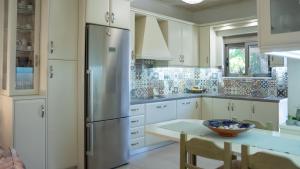 a kitchen with white cabinets and a stainless steel refrigerator at Η Αυλή της Μαρίας in Áyios Thomás