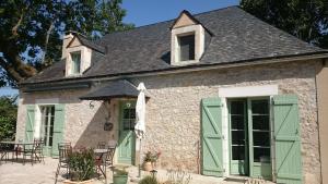 an old stone house with green doors and a patio at Les Bouyssières in Creysse